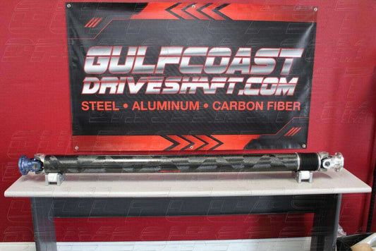 Carbon fiber driveshaft for 2018+ Jeep Grand Cherokee Trackhawk, featuring blue and silver aluminum components, displayed on a table.